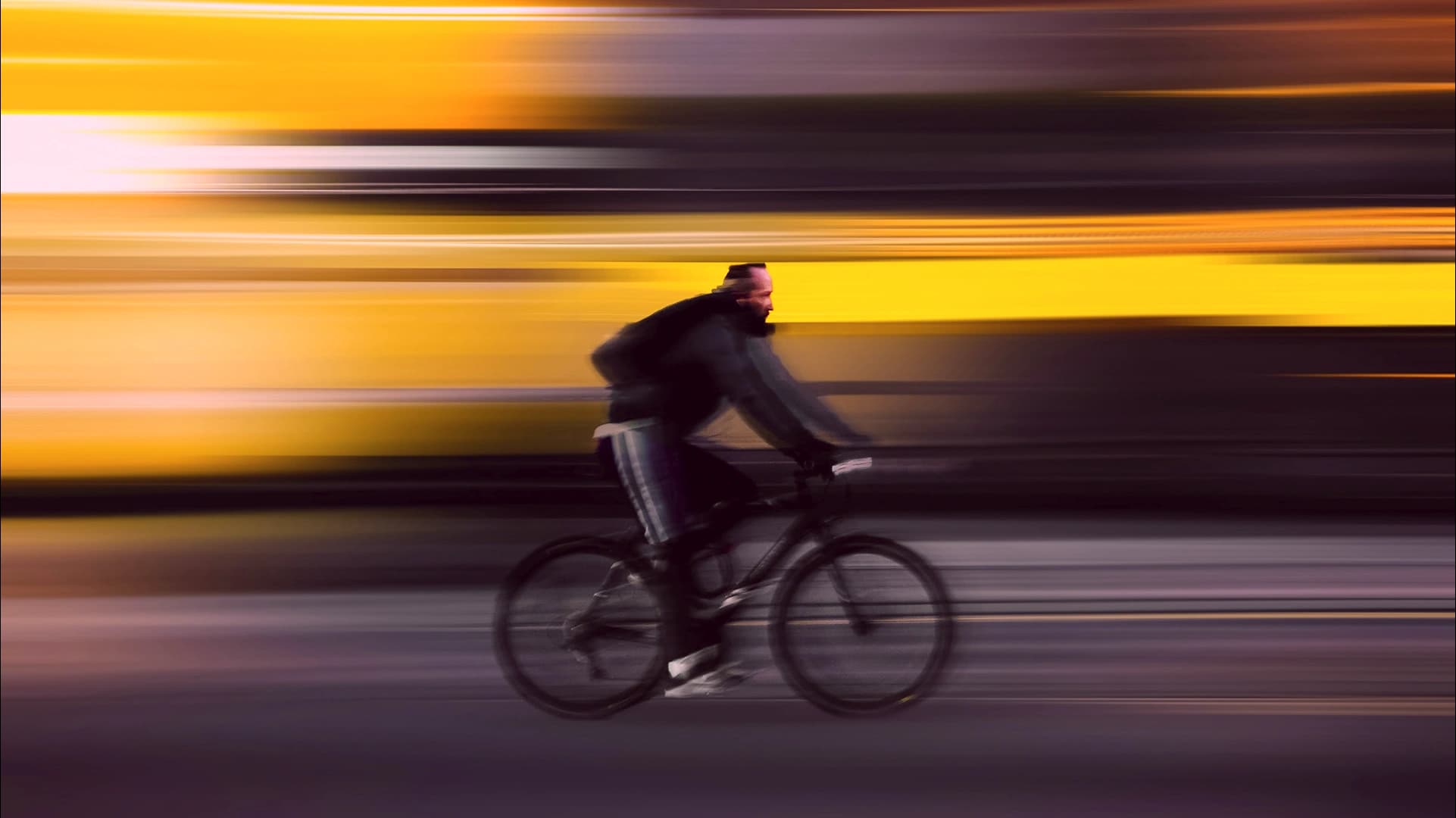 Cyclist riding quickly past a blurred yellow background.